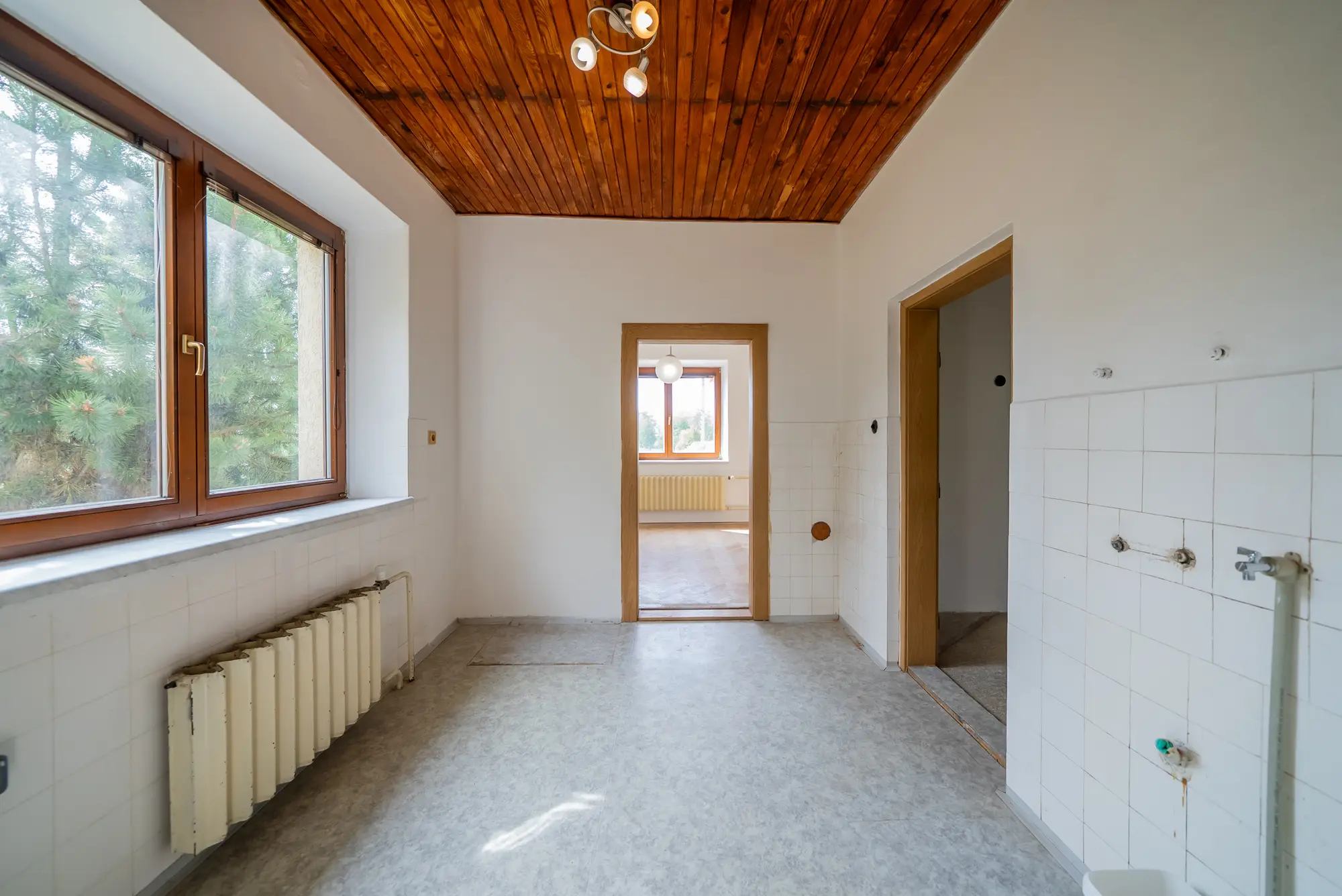 Kuchyně s obkladem stěn a oknem do zahrady