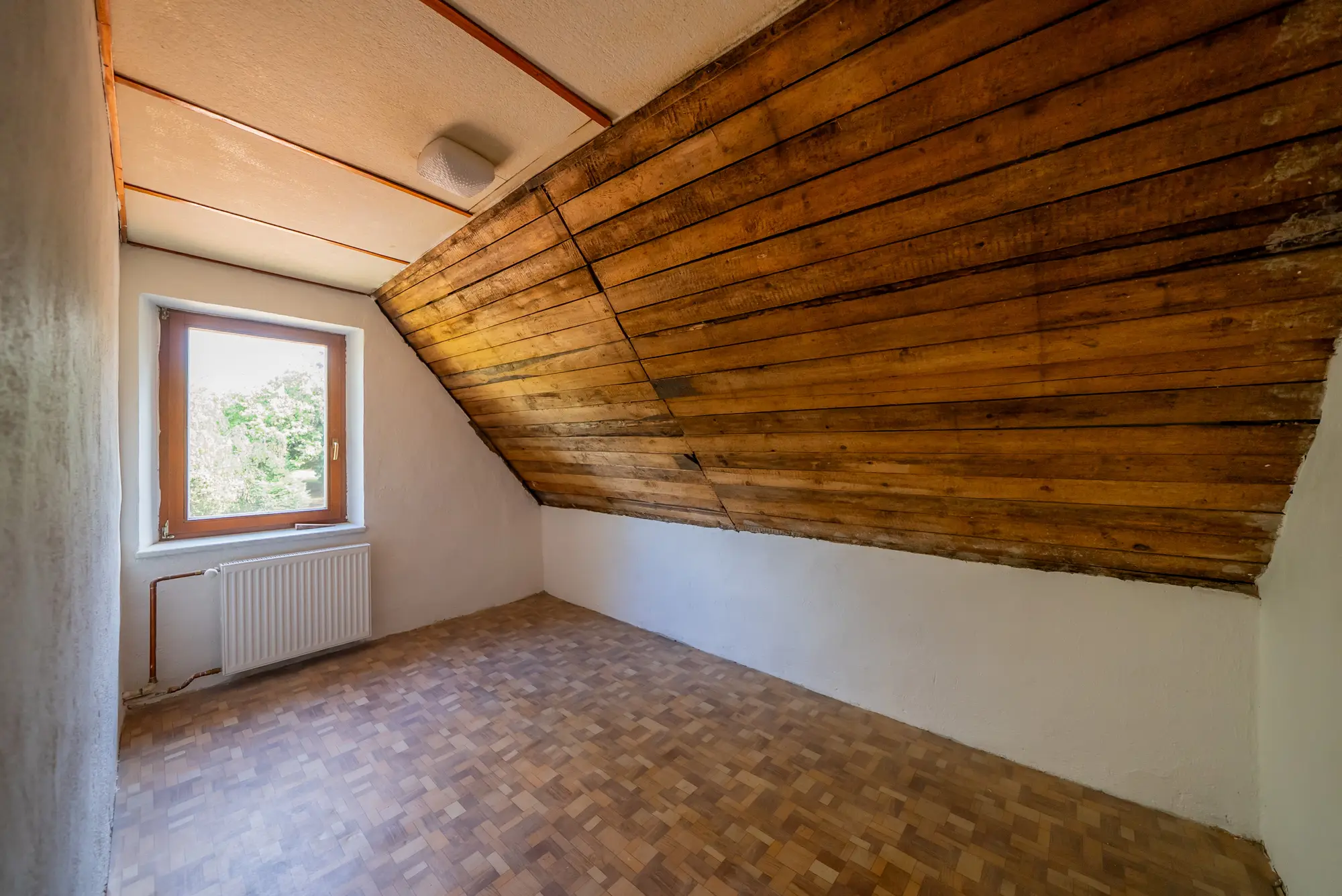 Pokoj v patře s dřevěným obkladem stropu